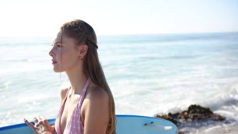 young caucasian woman stands by the sea, surfboard in hand, with copy space