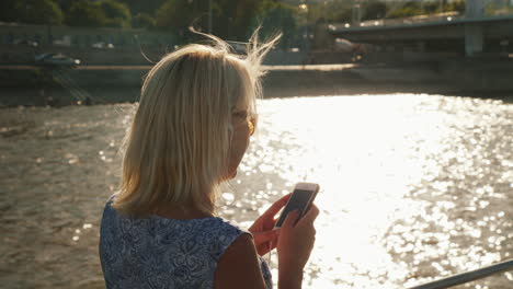 a young woman uses a smartphone sails on a river on a ship