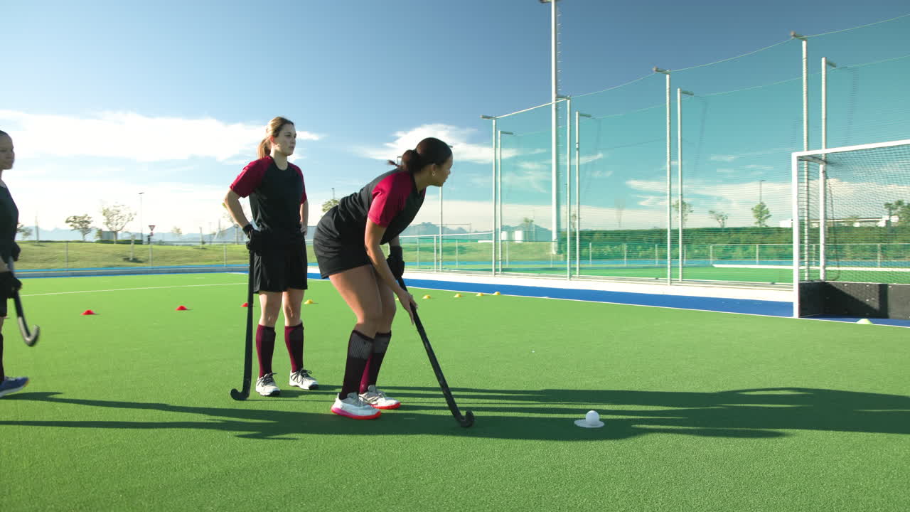 Practicing drills on sunny field, female hockey players focused on training