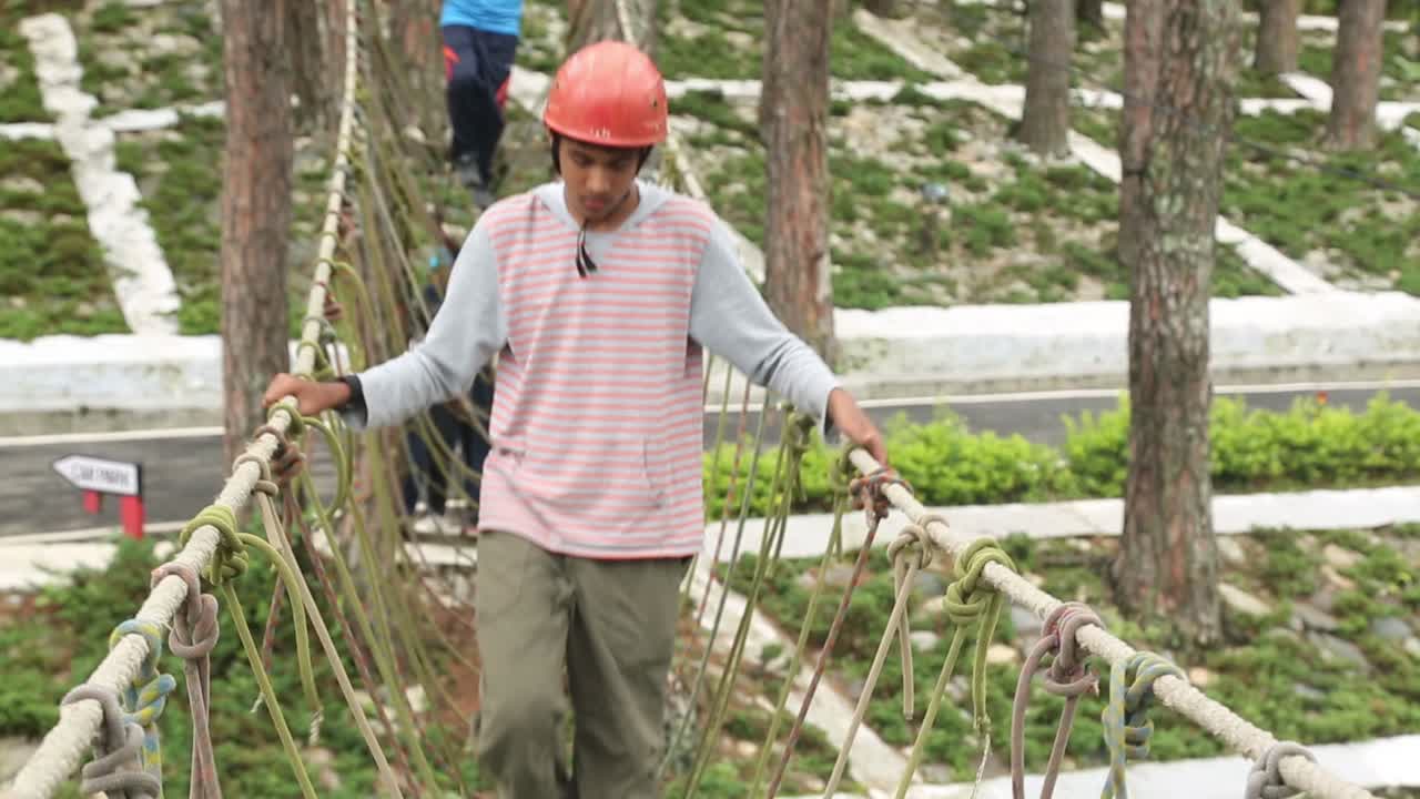 Boys Crossing a Rope Bridge in an Adventure Park