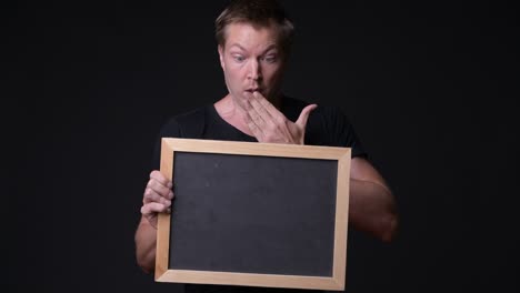 shocked and surprised man holding empty blackboard