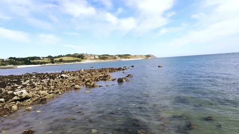 FPV-drone-flying-and-turning-above-rocky-craggy-Welsh-coastline-on-Menai-Strait-seafront