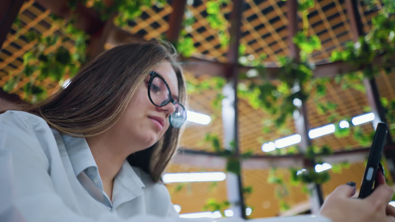 디지털 커뮤니케이션, 전문적인 환경 및 가상 협업을 강조하는 녹색과 함께 현대적인 작업 공간에서 전화로 외국 고객과 대화하는 원격 작업자의 클로즈업