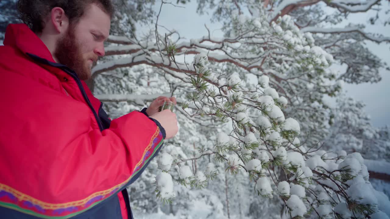 노르웨이 트론헤임에서 눈 내리는 겨울날 나무 잎사귀를 얻고 투명한 병에 넣는 사람