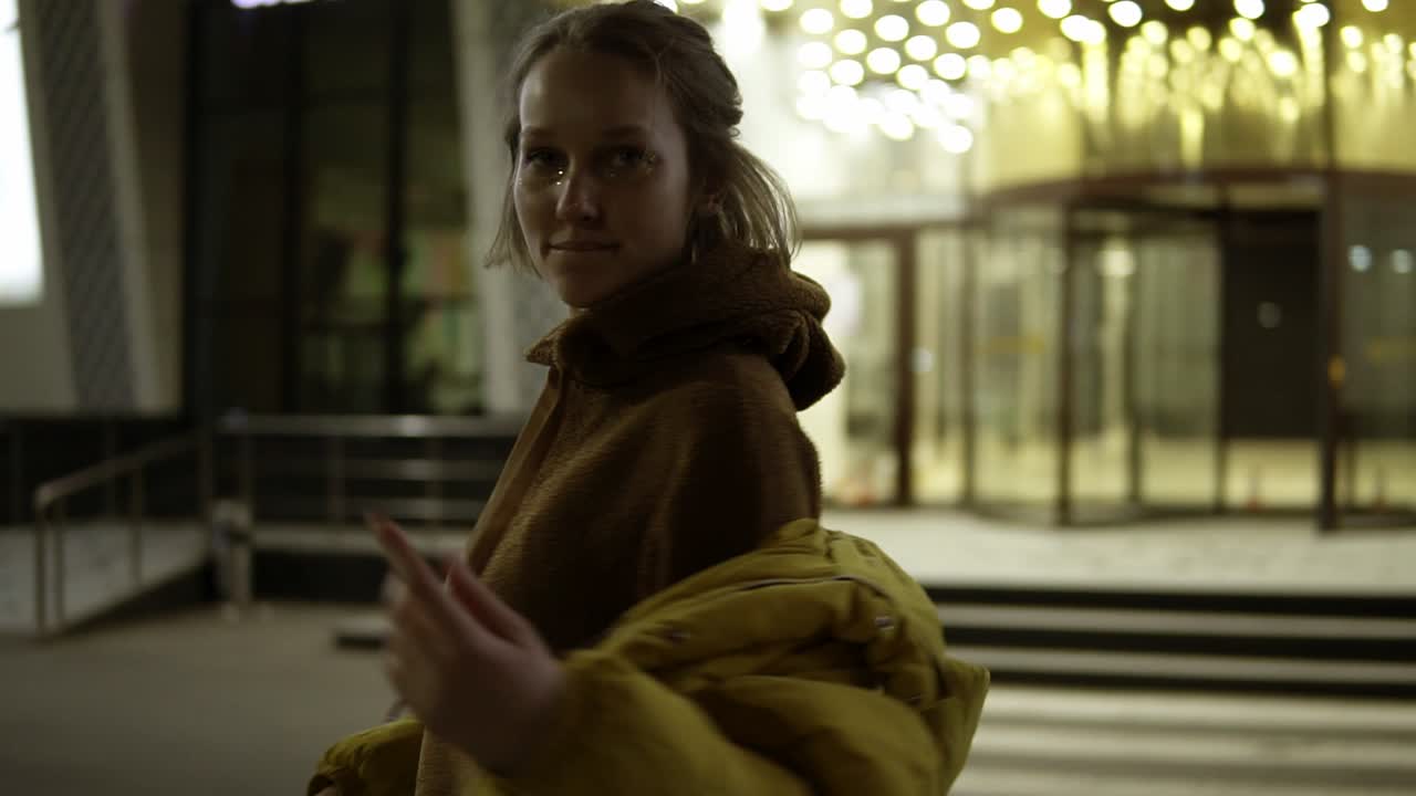 группа молодых и веселых людей сидит вечером у костра на пляже, жарит сосиски и играет на гитаре