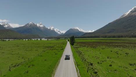 car driving on gravel road through remote green grass land in new zealand