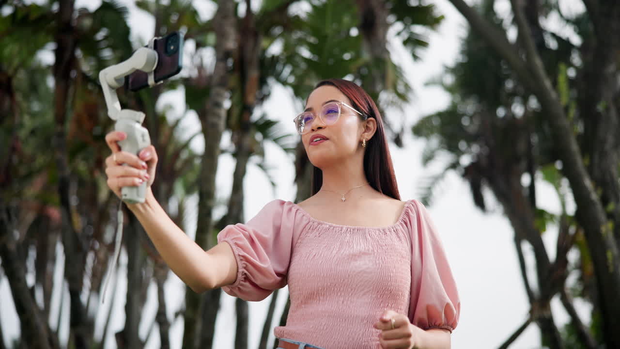 Woman vlogging outdoors with a smartphone stabilizer