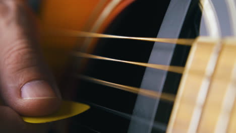 street musician plays brown acoustic guitar holding pick