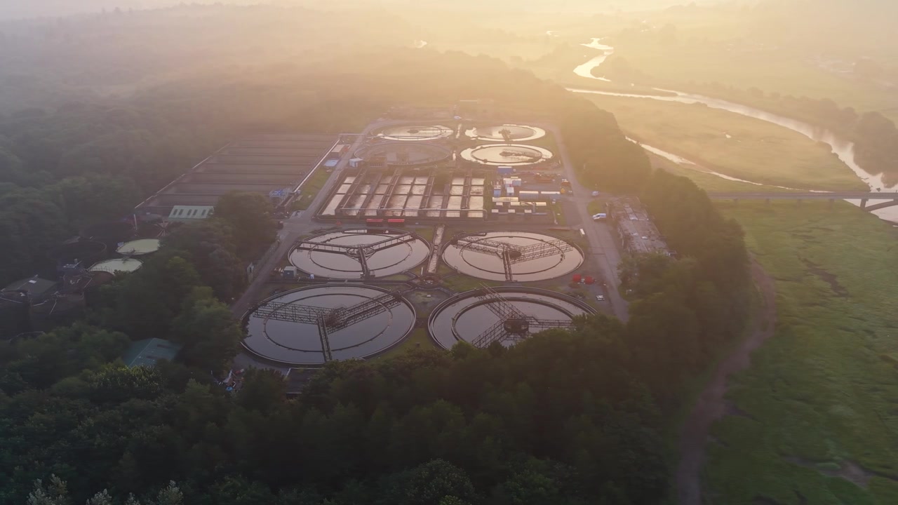 Water Treatment Plant and wastewater recycling facility at sunrise in Natural Landscape with nearby River. Clean tech, sustainability, and environmental engineering concept. Filmed in UK. 4K.