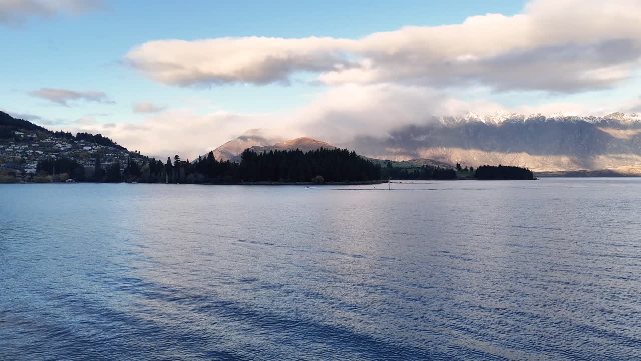 Aerial footage captures Queenstown's serene lake and mountain landscape under soft, natural lighting with gentle camera movement