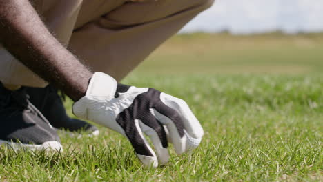 afrikaans-amerikaanse man die een golfbal op de golfbaan zet.