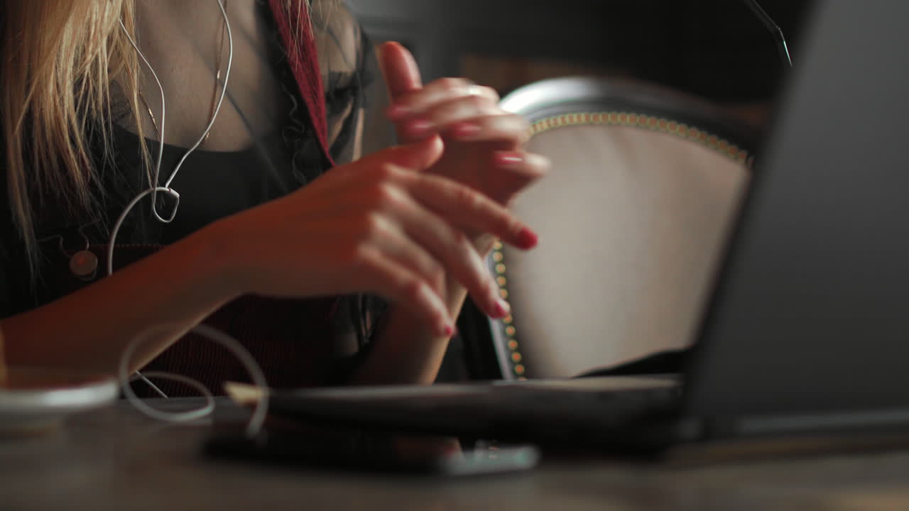 mujer con auriculares y participando en una llamada de videoconferencia en una computadora portátil mientras trabaja desde una cafetería