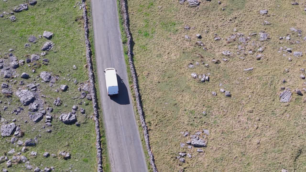 A delivery van drives on a winding road through the rocky landscape of The Burren, County Clare, Ireland