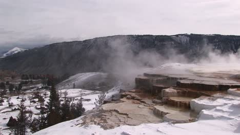 una mirada a las terrazas de piedra caliza de las aguas termales en invierno con pintorescas montañas al fondo