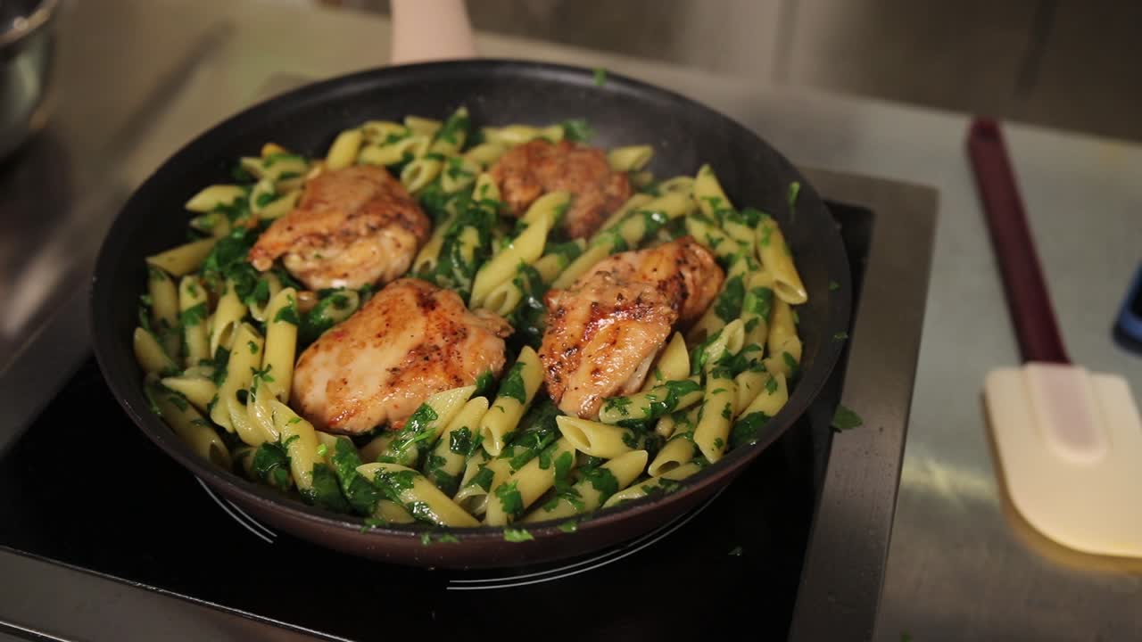 Cocinando pollo a la sartén con pasta penne y espinacas