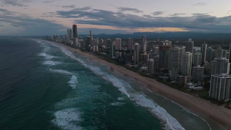 Gold-Coast,-Surfers-Paradise,-Queensland,-Australia,-drone,-Beachfront-cityscape-alight-at-sunset