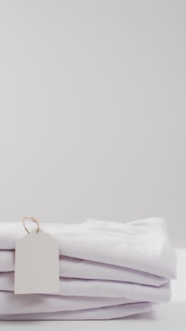 vertical video of stack of folded white t shirts with copy space on white background