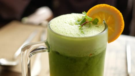 batido verde con rebanada de naranja y menta