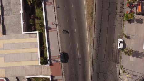 Top-down-view-of-a-man-running-on-the-street-of-Mar-del-Plata-in-Argentina-on-a-sunny-day-in-a-natural-background-beside-the-road-of-vehicles