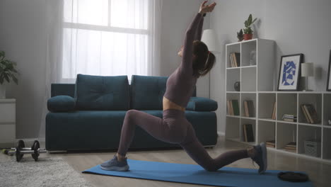 mujer deportiva delgada está entrenando sola en casa estiramiento entrenamiento para la flexibilidad de las articulaciones y la salud del cuerpo deportista en un apartamento moderno