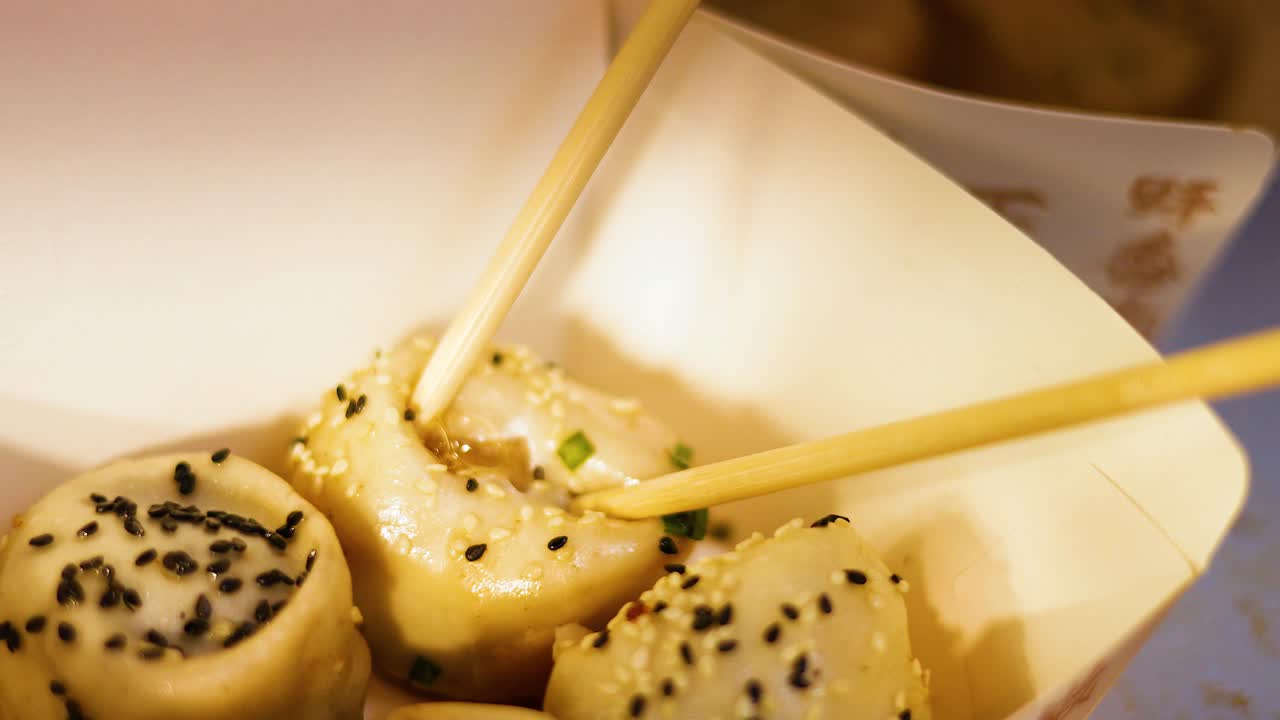 Chopsticks picking up pan-fried buns