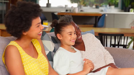 Multi-Generation-Female-Family-Relaxing-Sitting-On-Sofa-At-Home-Together-Watching-TV