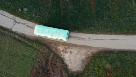 turquoise vanbus driving on a road, drone top view