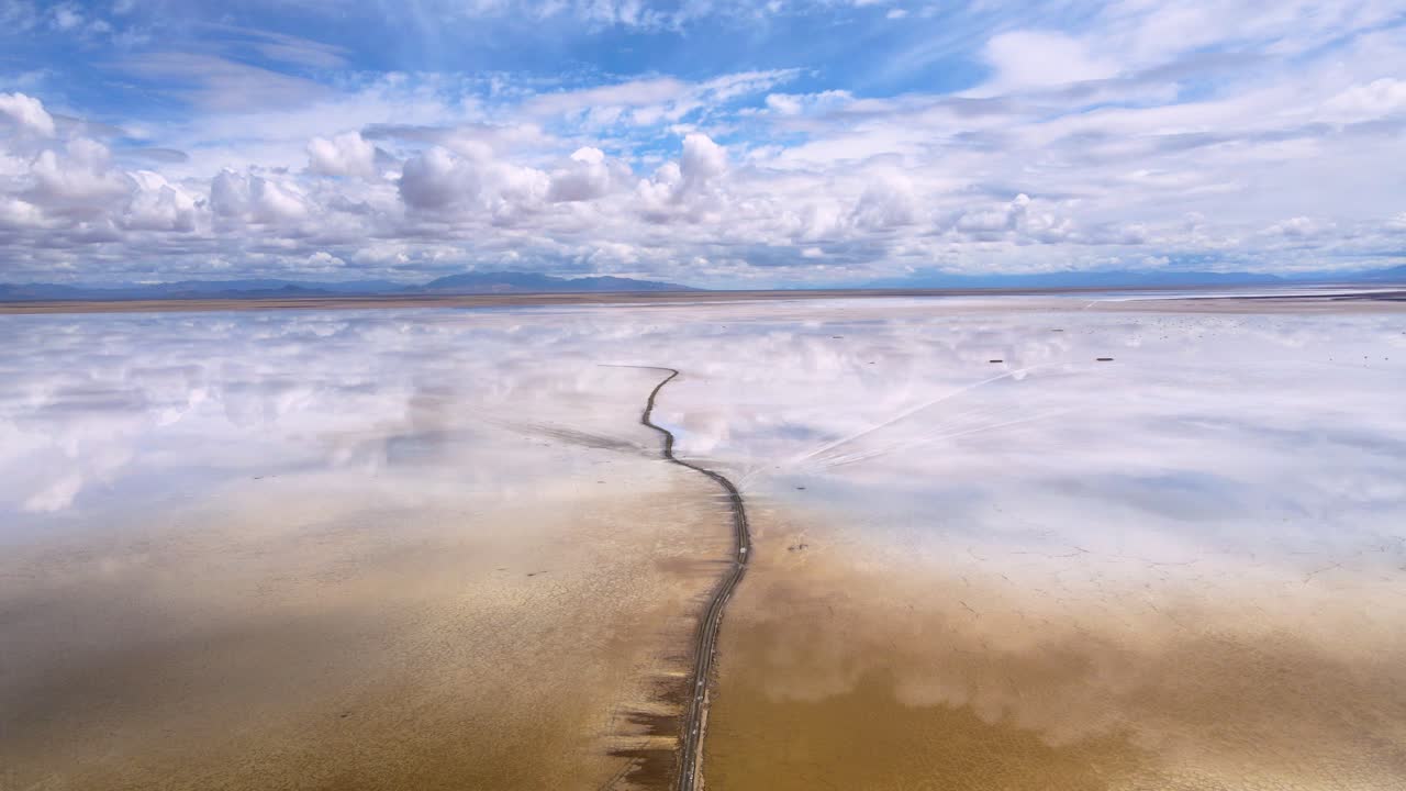 drone filmado volando sobre el lago salado de salinas grandes en la frontera de salta y jujuy, argentina siguiendo un camino de tierra