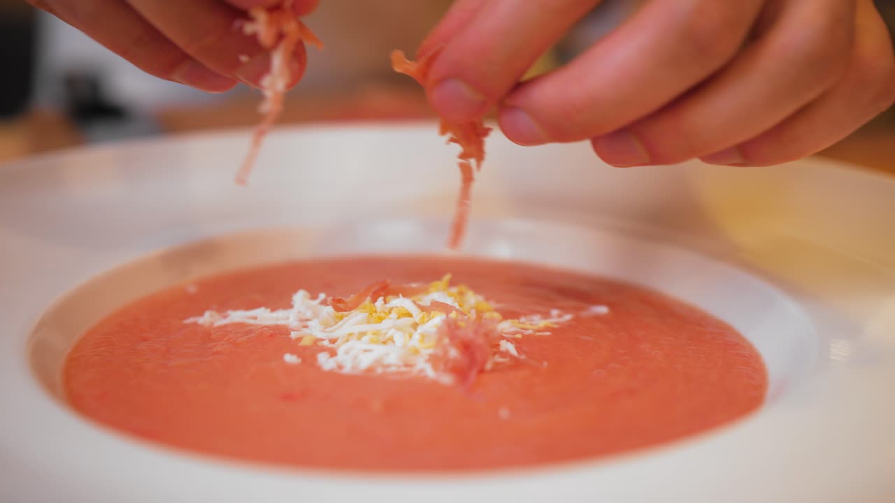 the chef decorates the gazpacho with ham
