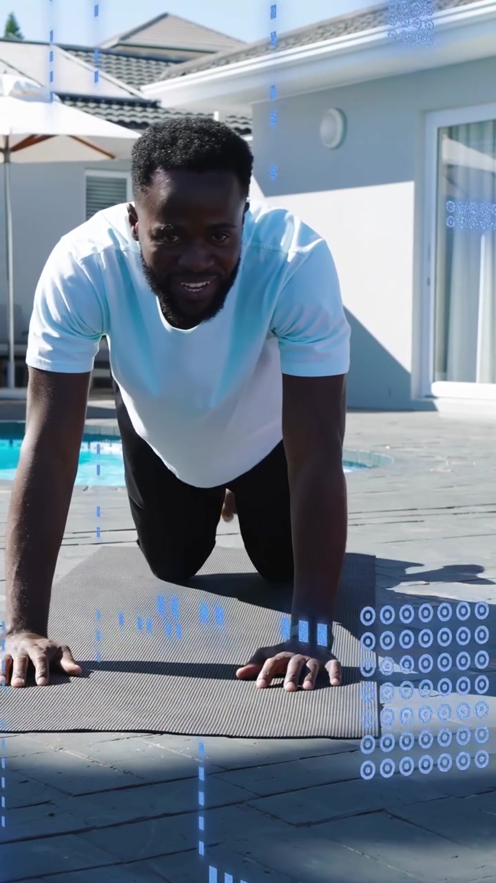 Vertical video: Man approaching mat by pool, moving into kneeling plank for fitness, blue HUD torso