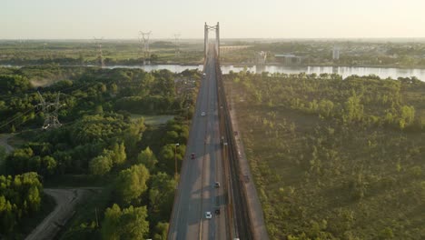 Aerial-shot-flying-over-cars-crossing-Zarate-Brazo-Largo-bridge-at-golden-hour