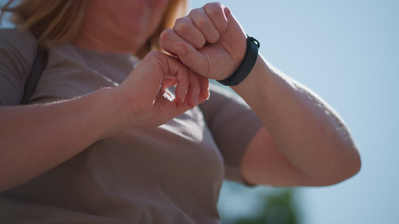 Close up of office assistant raising wrist to check time on smartwatch during sunny day, warm daylight illuminating casual outfit, blurred background with soft bokeh