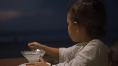 chica joven comiendo helado derretido, goteando de su cuchara, luego haciendo un baile de hombro con placer