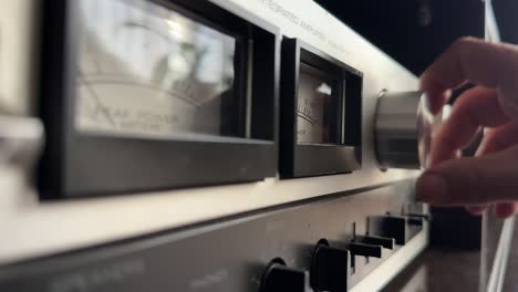 hand adjusting volume knob on vintage hi-fi stereo