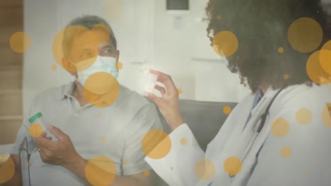 Animation-of-yellow-spots-over-diverse-female-doctor-and-male-patient-with-face-masks-on