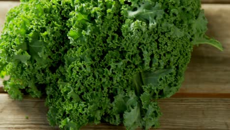animation of 100 percent natural text over green kale on wooden background
