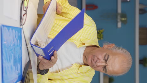 Vertical-video-of-Home-office-worker-old-man-examining,-analyzing-documents.