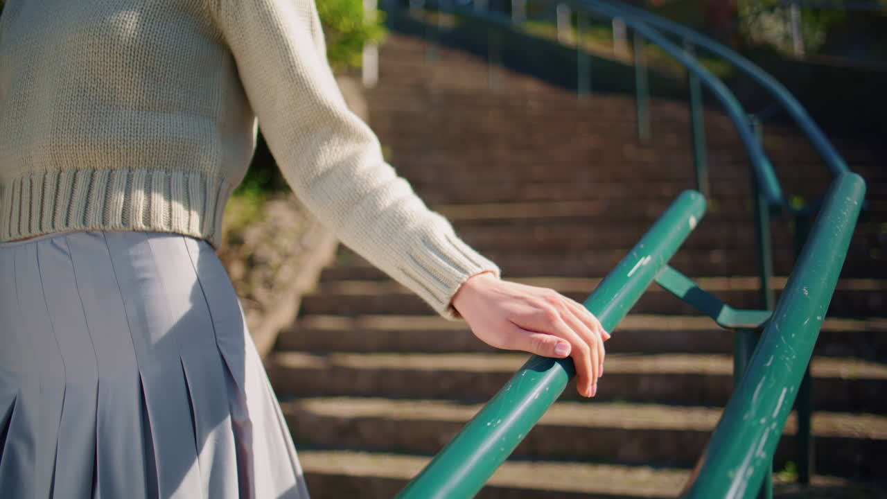 Woman hand touching rails walking sunshine staircase closeup. Lady relaxing