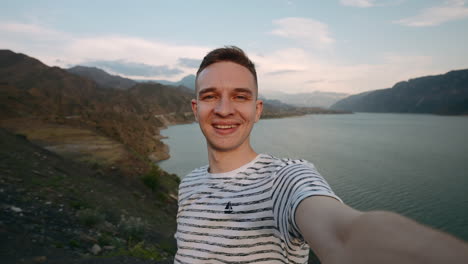 man taking a selfie by a mountain lake