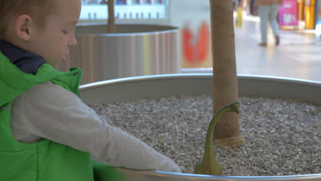 child playing with toy dinosaur in shopping mall