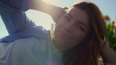 romantic blue-eyed woman relaxing in soft sunlight in tulip field background.