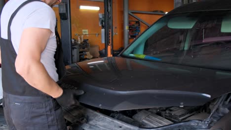 a mechanic inspecting and repairing a car engine with the hood open in a garage