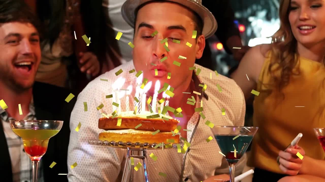 animación de confeti cayendo sobre un hombre feliz soplando velas en una fiesta de cumpleaños