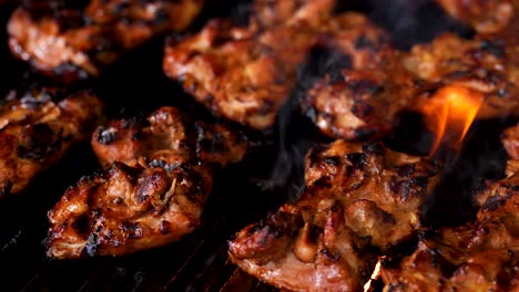 flame broiled barbecue chicken sizzling and grilling on a gas grill - close up panning shot to the right