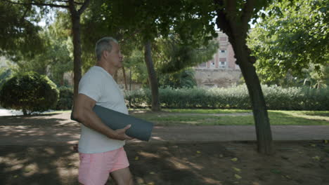 hombre en el parque con una alfombra de yoga