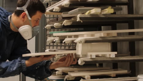 worker inspecting painted furniture parts in a paint booth