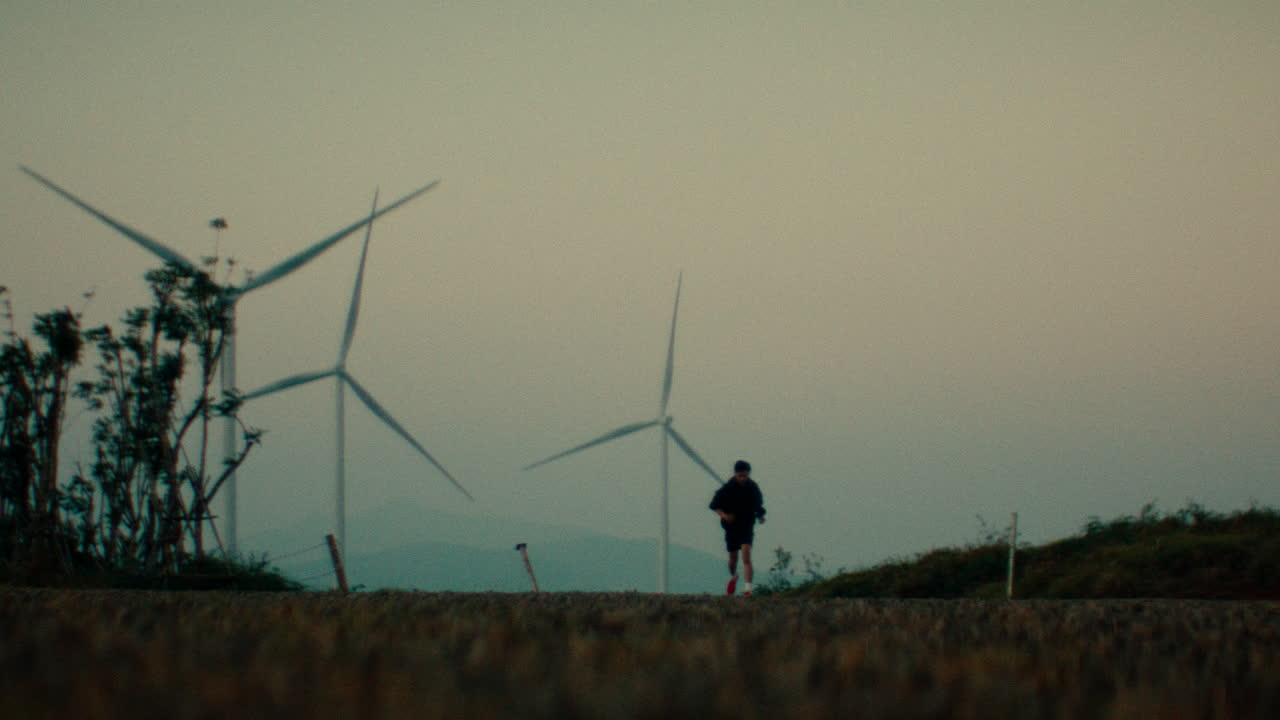 Man Running at Sunset by Windmills