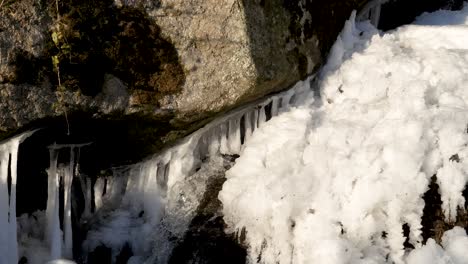 Bajo-Una-Gran-Roca-De-Granito-Brota-Una-Pequeña-Cascada-De-Una-Capa-De-Hielo