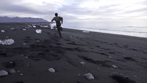 man running along seashore in winter