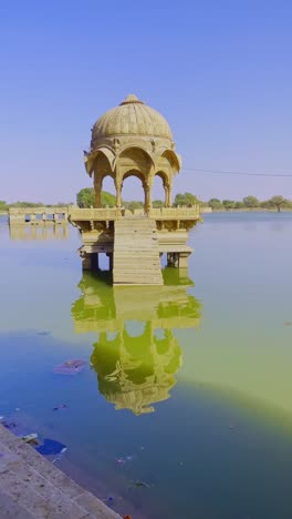 gadsisar lake in jaisalmer shimmers under the golden rajasthan sun, reflecting ancient pavilions in its calm waters. offers a serene escape amid the timeless desert beauty of india 4k